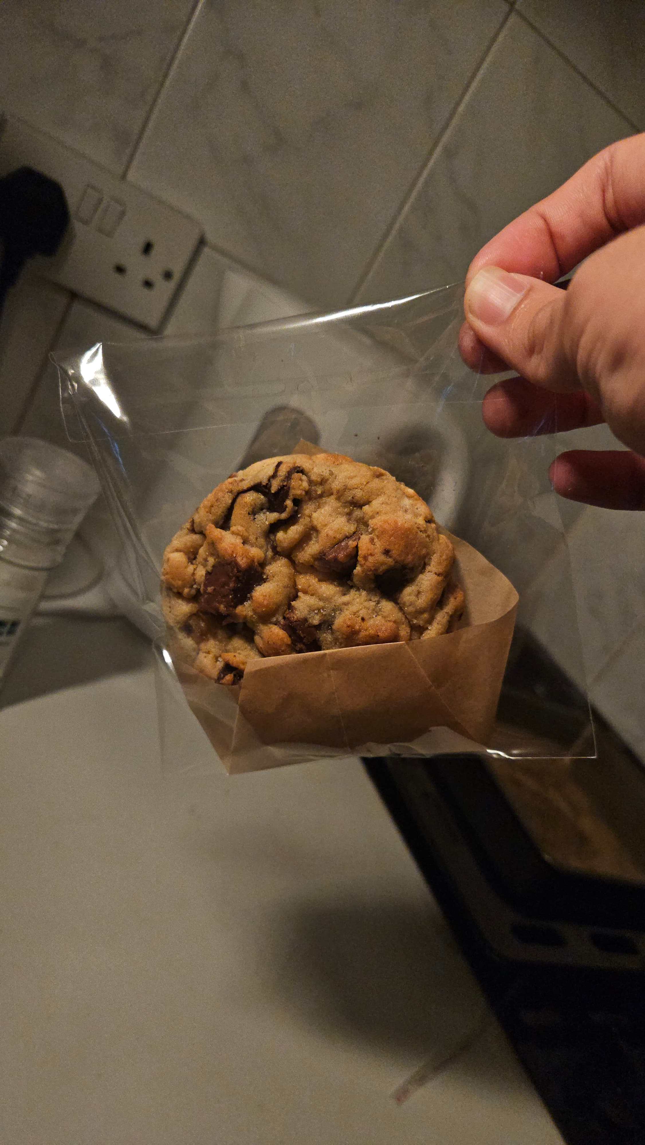 A wrapped cookie held over the kitchen counter.